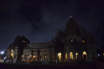 A domed temple under a dark night sky with lights at its doors