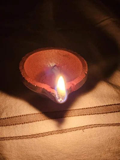A single clay lamp glowing in the dark on a festival night
