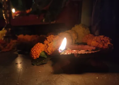 A lit clay lamp beside marigold garlands in warm evening light