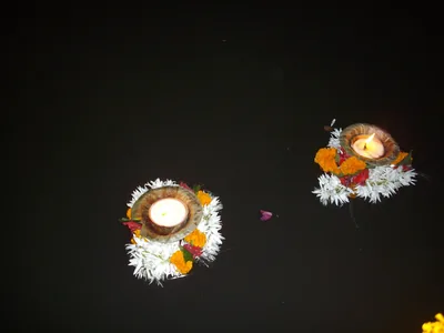 Leaf-cup lamps with marigolds floating on a dark river at night