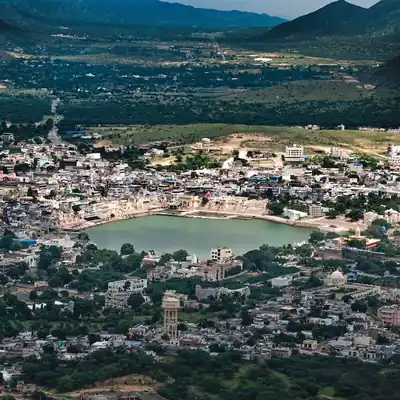 A view from a hill of a town around a sacred lake, with hills behind