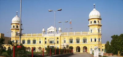 A yellow and white gurdwara under a clear blue sky