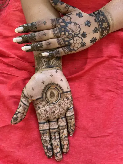 Hands with detailed mehendi designs resting on a red cloth