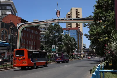 A busy street in Nairobi with a bus, tall buildings and an arch