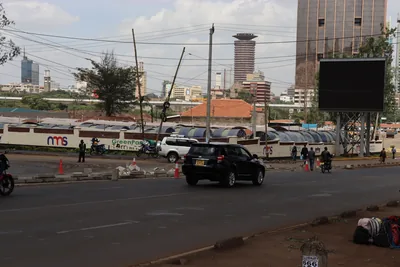 A view of the Nairobi skyline with a tall round tower behind a road