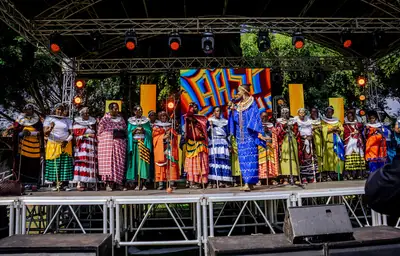 Dancers in bright beaded clothes perform together on an outdoor stage