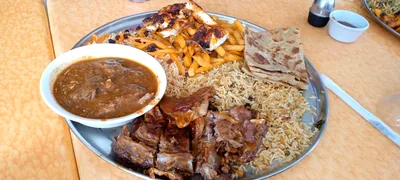 A platter of grilled meat, rice and sauces