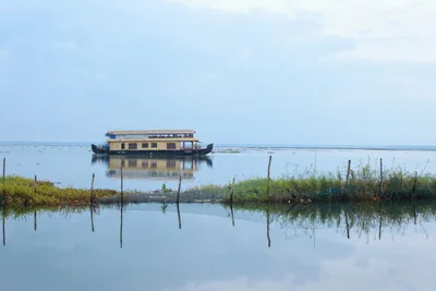 A Kerala houseboat on calm backwaters with its reflection and green banks
