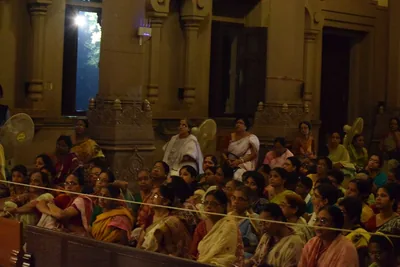 A large crowd of devotees seated in a temple hall at night