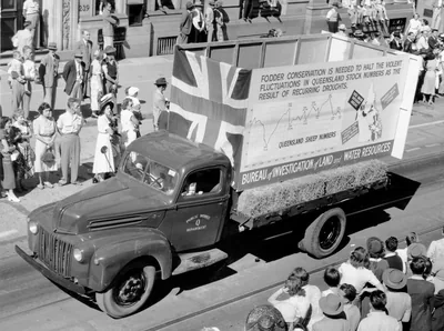 A truck float carrying a big banner in an old street parade
