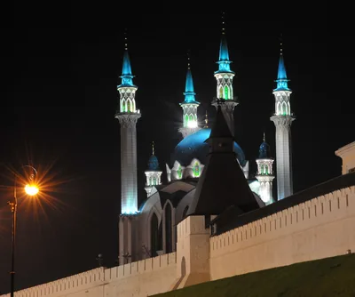 A mosque with blue domes and lit minarets at night