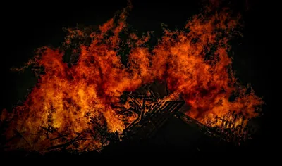 Tall orange flames of a winter bonfire at night