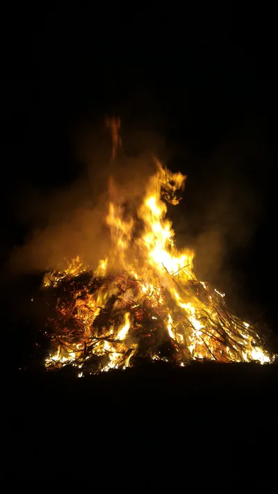 A tall Lohri bonfire of stacked wood blazing bright orange against the night