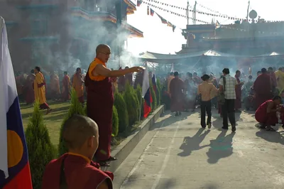 A monk offers incense as smoke drifts over a monastery yard