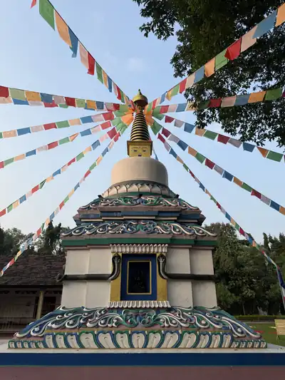 A white stupa under strings of colourful prayer flags