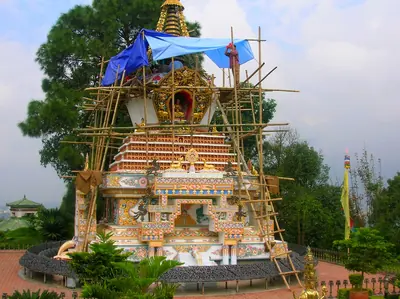 A tall painted stupa being decorated