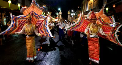 Dancers in bright traditional costumes perform in a lit street at night