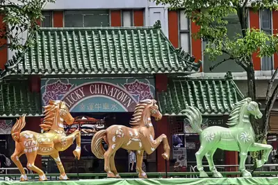 Painted horse statues in front of a green tiled Chinatown gate