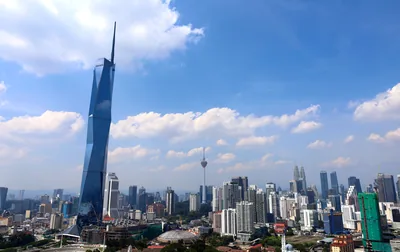 The Kuala Lumpur skyline with a very tall glass tower and blue sky