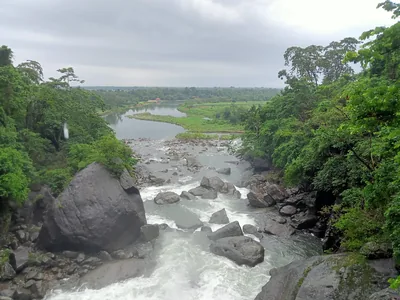 A clear river rushing over boulders between green banks