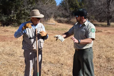 Two men in hats talking as they work on a dry field