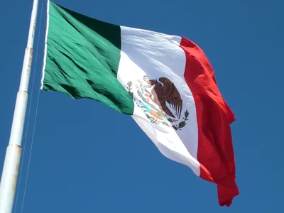 The flag of Mexico waving against a blue sky