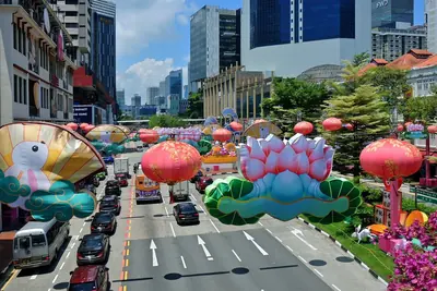 A city street with giant lotus and lantern decorations over the road