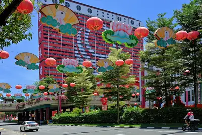 A tall building behind trees and red lanterns with festival displays