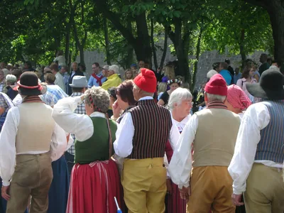 People in folk costumes with red caps and striped skirts in a crowd