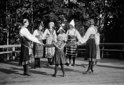Black and white photo of people in folk dress dancing in a ring
