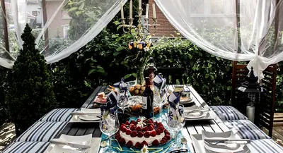 An outdoor table set with glasses, flowers and a strawberry cake