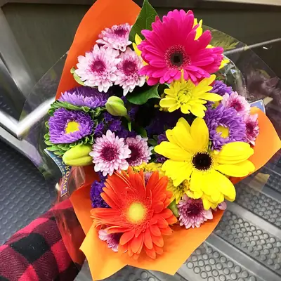 A bright bouquet of gerberas, daisies and chrysanthemums wrapped in orange paper