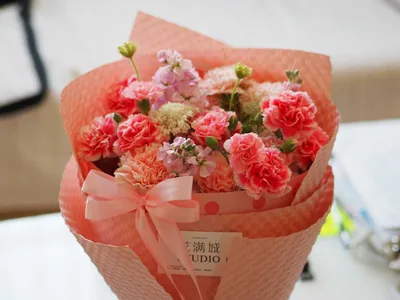 A wrapped bunch of pink carnations with a ribbon