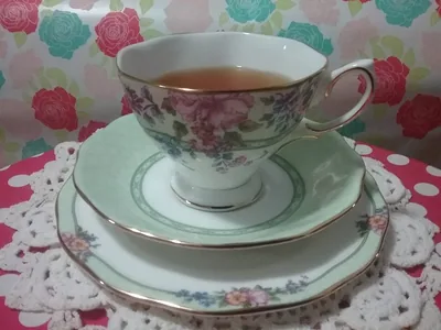 A floral china tea cup and saucer on a flowered cloth