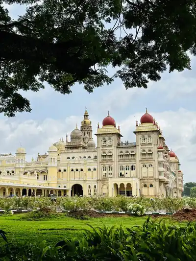 The Mysore Palace with red domes behind green gardens