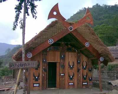 A traditional Angami house with carved wooden front and crossed horns on the roof