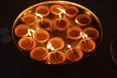 A steel plate holding many lit clay lamps
