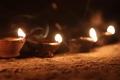 A row of small clay lamps burning on the ground