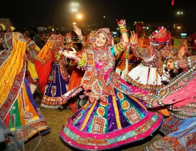 Dancers in bright mirror-work skirts whirling in a circle at night