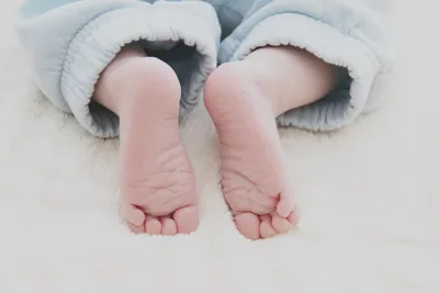 Two tiny baby feet peeking out from soft blue clothes
