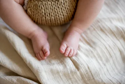 Small baby feet resting on a cream blanket