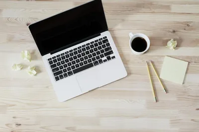A laptop and a cup of coffee on a light desk