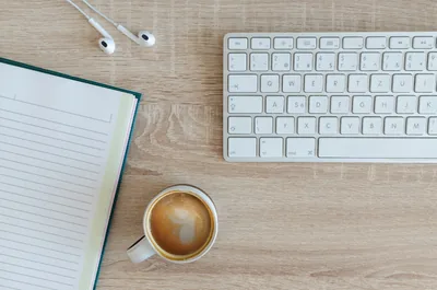 A desk with a keyboard, notebook and coffee