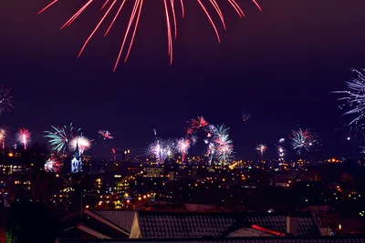 Red and white fireworks over the rooftops of a city at night