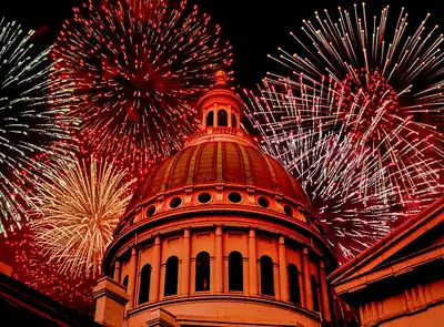 Fireworks bursting around a lit dome building at night