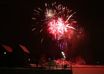 Red and white fireworks glowing above the shore at midnight
