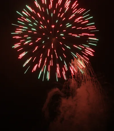 A large red and green firework against the night sky
