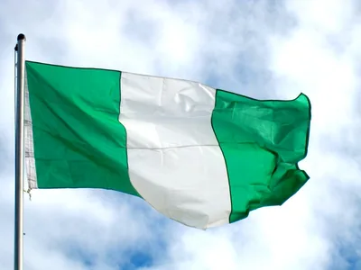 The green and white flag of Nigeria waving against white clouds