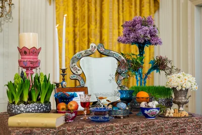 A haft-sin table with a mirror, candles, sprouts, flowers and painted eggs