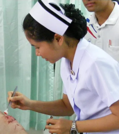 A nurse in a white cap writing notes in a hospital